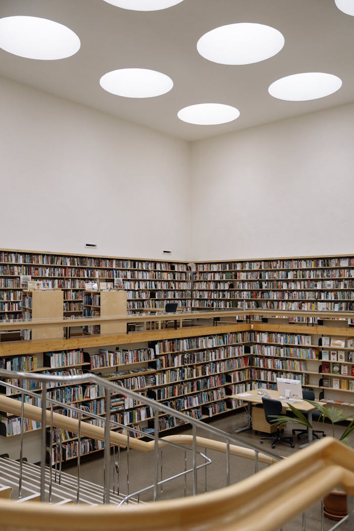A spacious modern library with high bookshelves, skylights, and open reading areas.